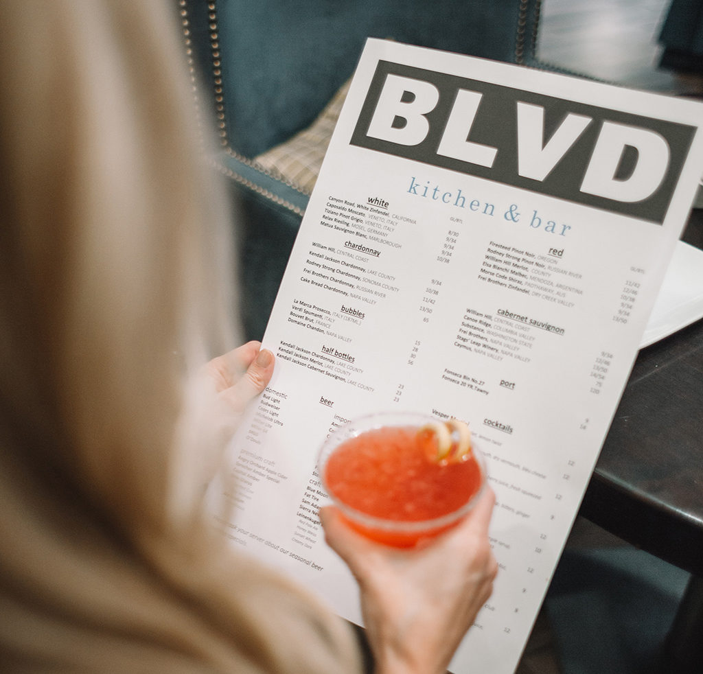 woman holding a menu and a colorful drink