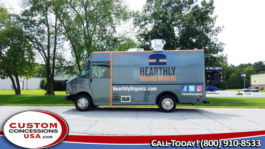 gray food truck parked under some trees