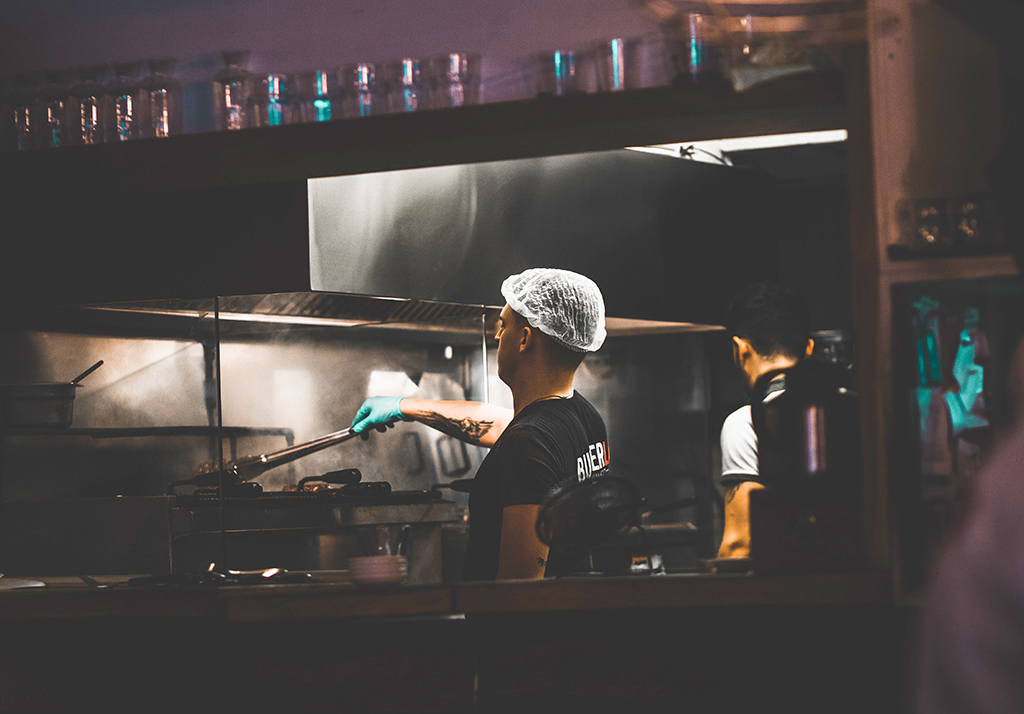 man wearing a hairnet working in a restaurant kitchen